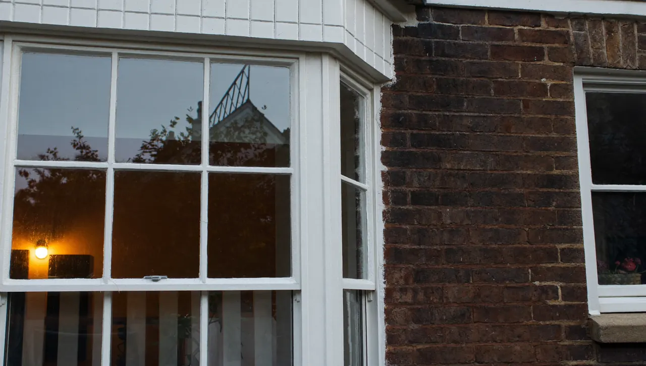 Double glazed sash windows on a brick terraced house at dusk